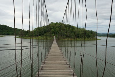 Footbridge over river against sky