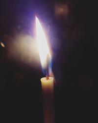 Close-up of illuminated candle against black background