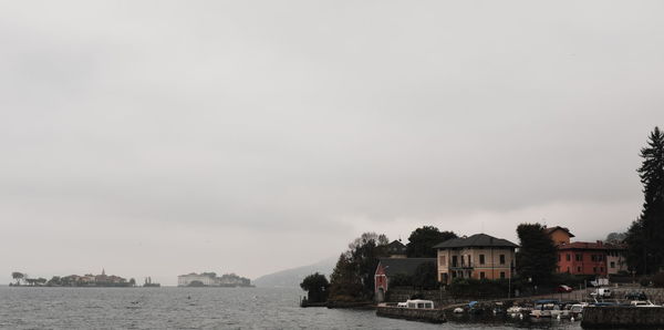 Houses by sea against sky in city