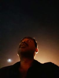 Low angle view of man looking at camera against sky at night