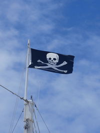 Low angle view of pirate flag against sky