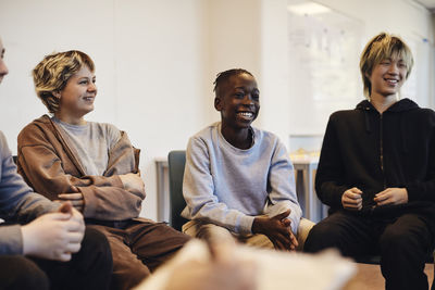 Happy teenage boys and girl sitting together in group therapy