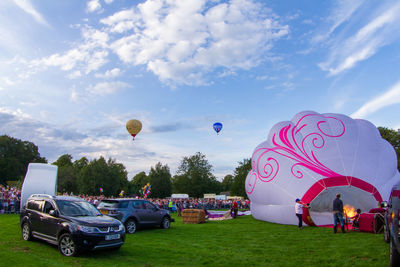 View of hot air balloons on field against sky