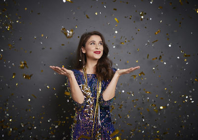 Portrait of beautiful young woman standing against gray background