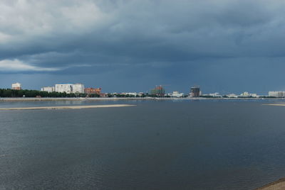 Sea by buildings against sky in city