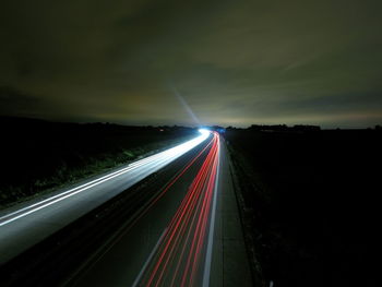 Light trails on road against sky at night