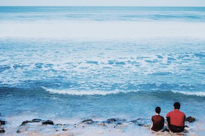 Rear view of people at beach against sky