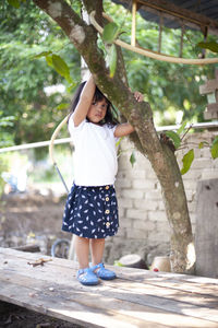 Full length of girl standing by tree on wooden table