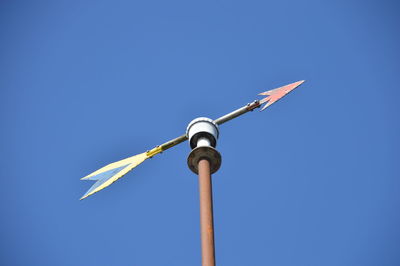 Low angle view of weather vane against clear blue sky