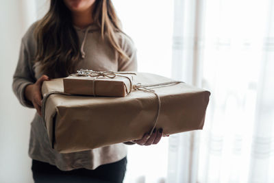 Woman holding camera while standing at home