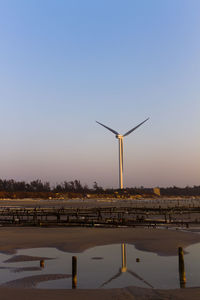 Wind turbines on landscape against clear sky during sunset
