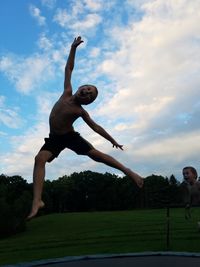 Low angle view of man jumping against sky