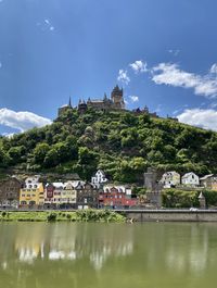 Buildings by river against sky