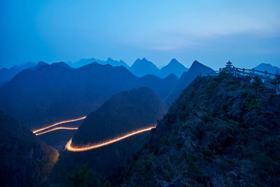 Aerial view of illuminated mountains against blue sky