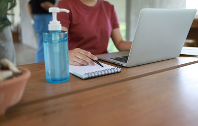 Midsection of woman using laptop on table