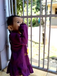 Girl looking away while standing against window