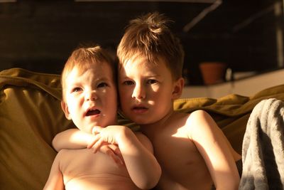 Two wonderful boys are hugging. the older brother has brown hair , the younger brother is blond 