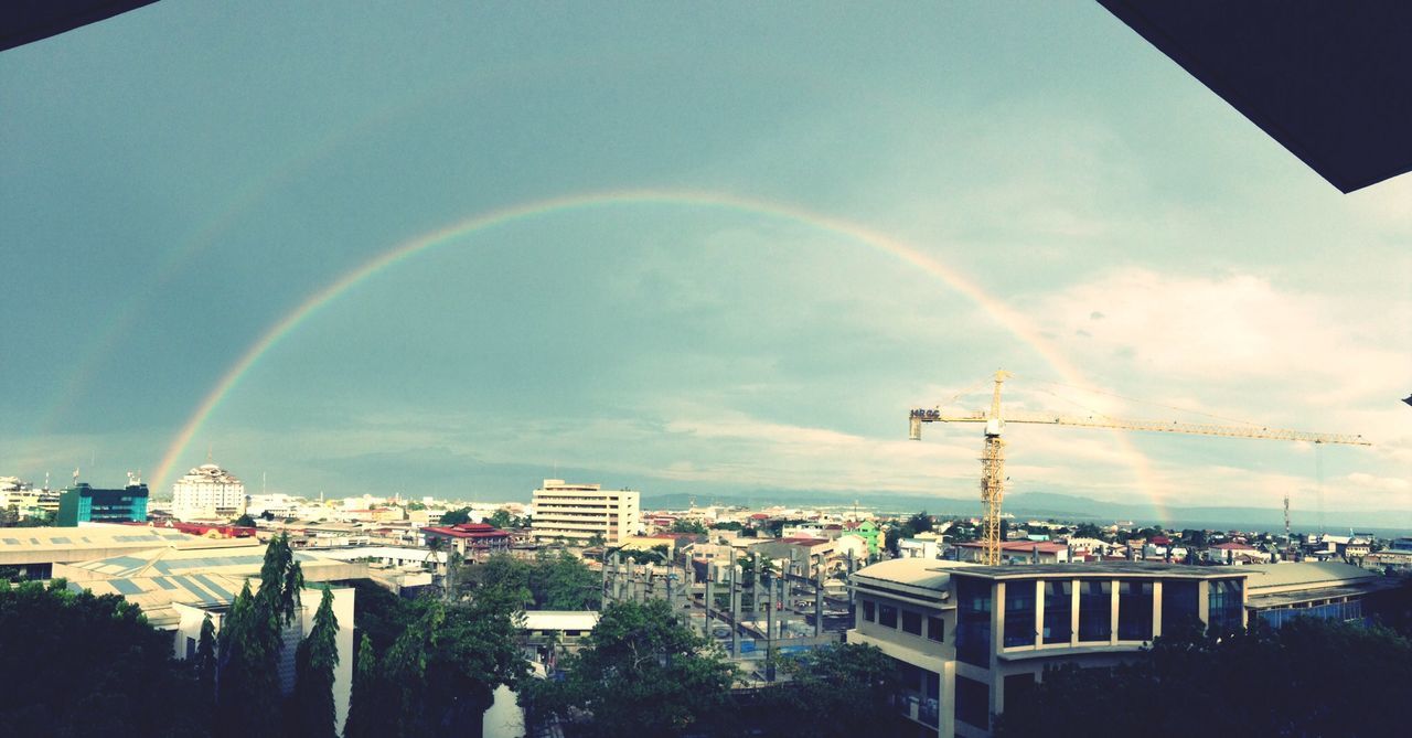 building exterior, architecture, built structure, sky, rainbow, cloud - sky, tree, city, cloud, cloudy, house, blue, multi colored, residential building, residential structure, outdoors, panoramic, low angle view, residential district, no people