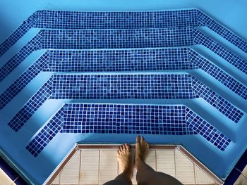 Looking down at feet standing near the pool steps