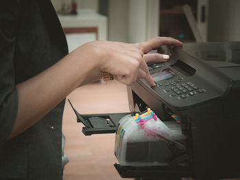 Midsection of woman using computer printer