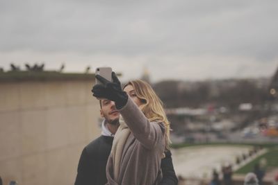 Young woman standing outdoors against sky during winter