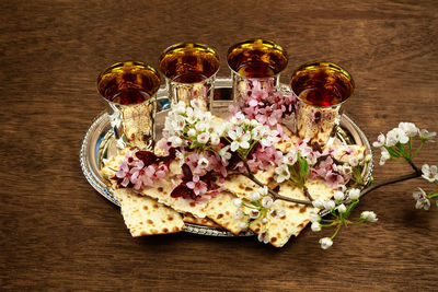 High angle view of crackers with flowers and drink in tray on table