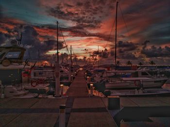 Sailboats moored at harbor during sunset