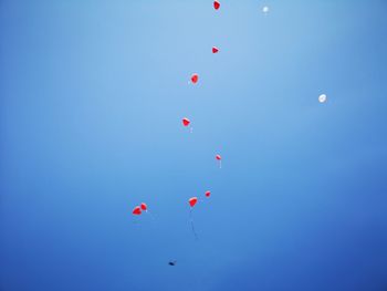 Low angle view of balloons flying against blue sky