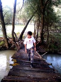 Full length of boy standing by tree against lake