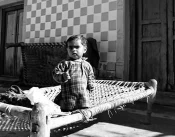 Portrait of boy sitting on cot outdoors