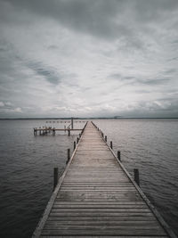 Wooden pier over sea against sky