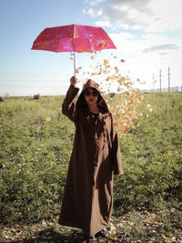 Woman with umbrella standing on field