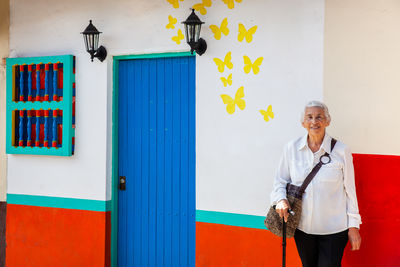 Portrait of smiling young woman standing against wall