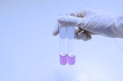 Cropped hand of scientist wearing surgical glove holding test tubes in laboratory