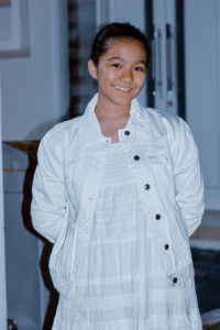 A young girl in white dress and white jacket posing for the camera at night