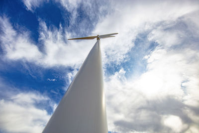 Wind turbine low angle against cloudy blue sky
