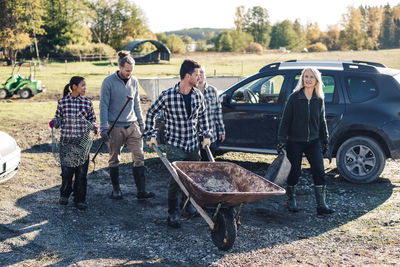 Multi-ethnic male and female farmers with various equipment at organic farm