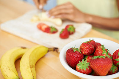 Midsection of woman holding strawberries on table