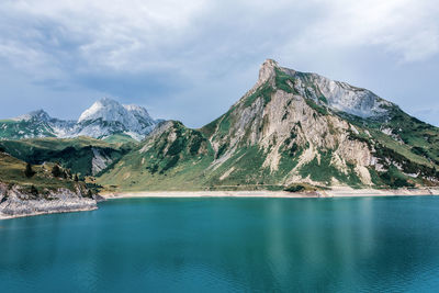 Scenic view of lake by mountains against sky