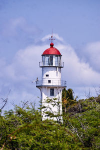 Low angle view of lighthouse by building against sky