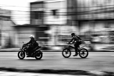 Rear view of man riding motor scooter on street