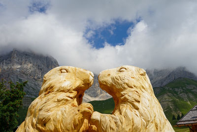 Statue of mountain range against cloudy sky