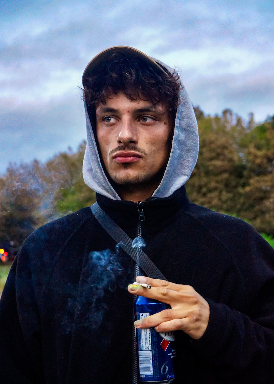 PORTRAIT OF YOUNG MAN HOLDING CAMERA