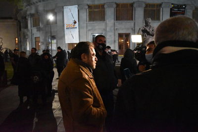 People on street against buildings at night