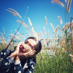 Portrait of smiling young woman on field against sky