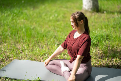 Side view of a young woman sitting on field