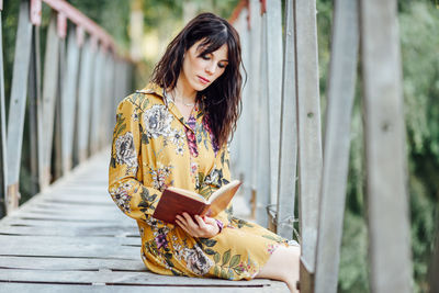 Young woman looking away while sitting on railing