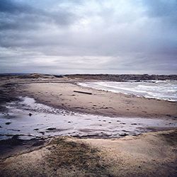 Scenic view of beach against cloudy sky