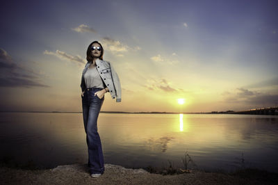 Man standing in lake against sky during sunset