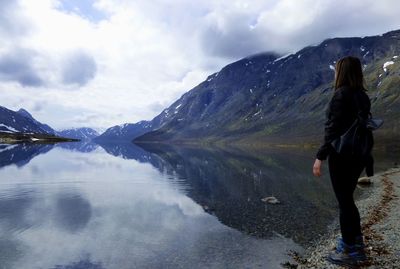 Woman standing at lakeshore against sky